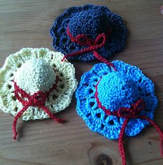 three crocheted hats sitting on top of a wooden table