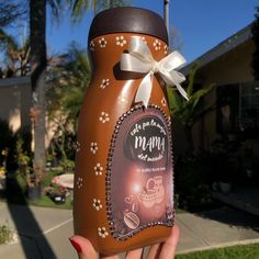 a person holding up a chocolate covered jar with a bow on it's handle