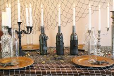 a table topped with lots of bottles filled with candles next to plates covered in wire