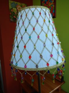 a lamp that is on top of a wooden table next to a green wall and painting