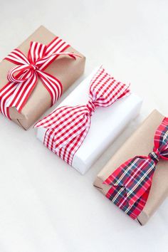 three wrapped presents with red and white bows are sitting next to each other on a table