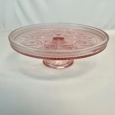 a pink glass cake plate sitting on top of a white table