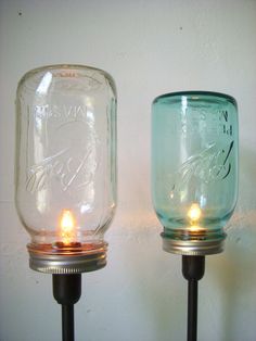 two mason jars sitting next to each other on top of a metal stand with candles in them