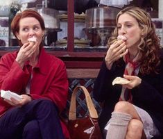 two women sitting on a bench eating food