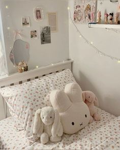 two stuffed animals sitting on top of a bed in a room with white walls and lights