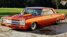 an orange car parked on top of a dirt road