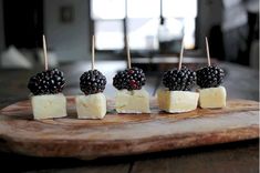 four pieces of cheese with blackberries on them