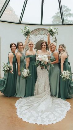 a bride and her bridesmaids pose for a photo in front of a glass dome