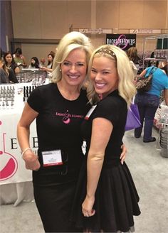 two women standing next to each other in front of a table