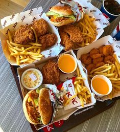 several trays of food including chicken, french fries and coleslaw on a table