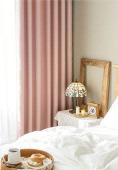 a tray with donuts on top of a bed next to a lamp and window