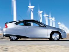 a silver car parked in front of wind turbines