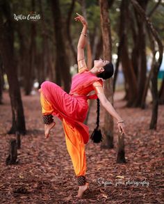 a woman in an orange and red outfit doing a yoga pose with her hands up