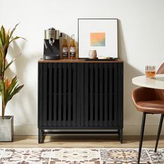 a black cabinet sitting on top of a wooden floor next to a potted plant