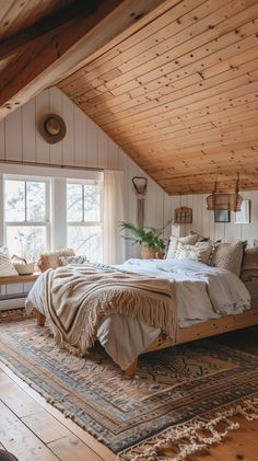 a large bed sitting in the middle of a bedroom next to a window on top of a wooden floor