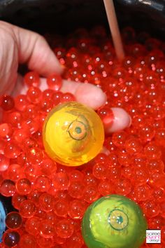 two balls with eyes on them are being held by a person's hand in front of some red and green beads