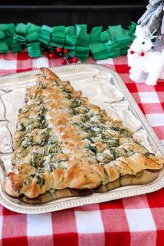 a christmas tree shaped pastry sitting on top of a metal tray next to a white and red checkered tablecloth