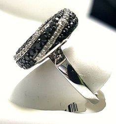 Dainty and darling, this black and white diamond fashion ring is a great anytime look. Created in warm 14K White gold, this ring features a center cluster of alluring enhanced black diamonds with a frame of shimmering white accent diamonds. Simple yet so stylish, this ring delights with a very amazing gallery of flowery shape and a polished shine. Details: ►Metal: White Gold ►Gold Purity: 14K ►Diamond Weight: 2.50 carat ►Diamond Shape: Round Brilliant ►Diamond Clarity & Grade: GH-SI1 ►White Black Oval Cluster Ring For Anniversary, Black Oval Ring With Black Diamonds, Oval Black Rings With Black Diamonds, Black Oval Rings With Black Diamonds, Black Diamond Ring In Round Cut, Luxury Black Diamond Ring With Pave Setting, Black Diamond Rings With Round Cut, Elegant Black Cluster Ring For Promise, Modern Black Diamond Anniversary Ring