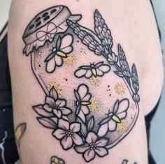 a woman's arm with flowers and a jar on it that says love is in the air