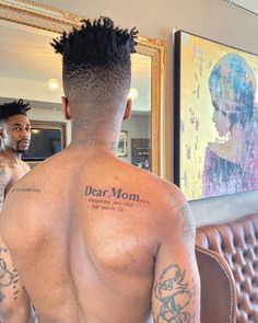 a man with tattoos on his back standing in front of a mirror