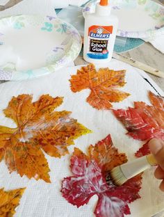 someone is painting leaves on a table cloth