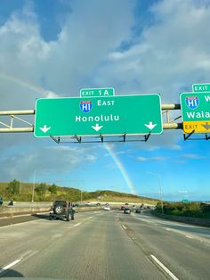 a rainbow is seen in the sky above a highway sign that reads honolutu and waiki