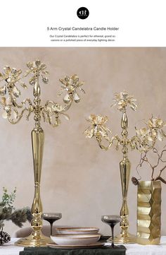 two gold vases with flowers in them sitting on a table next to each other