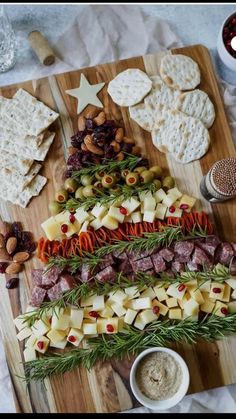 a wooden cutting board topped with cheese and crackers next to other food on top of a table