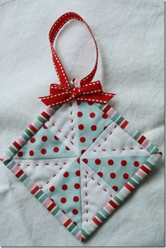 a quilted ornament with a red bow on it's neck hanging from a white cloth