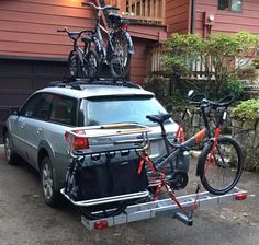 a car with two bikes on the back of it's roof rack in front of a house