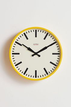 a yellow and white clock with black hands on a white surface, showing the time