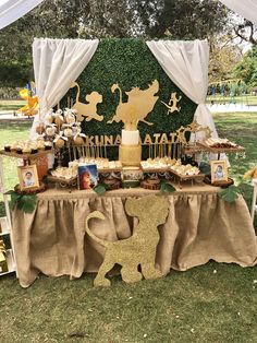 the dessert table is set up for an animal themed birthday party with gold and white decorations