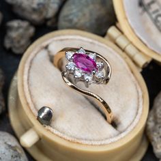 This pretty ring is centered with one (1) marquise cut ruby set into a four-prong setting. The ruby is bordered with eight (8), prong set, round brilliant cut diamonds. The ring measures 9.4mm at the top, rises 5.5mm above the finger, tapering to 1.8mm wide and 1.3mm thick at the base of the shank. This ring is currently a size 5.25. Vintage Ruby Rings, Ruby Ring Vintage, Pink Topaz Ring, Ruby Set, Ruby Rings, Pretty Ring, Pink Sapphire Ring, Natural Gemstone Ring, Ruby Engagement Ring