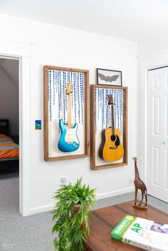 two guitars are hanging on the wall next to a giraffe and a bed