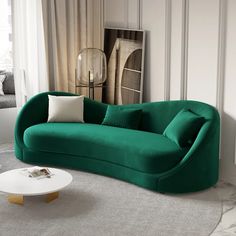 a green couch sitting next to a white coffee table in a living room under a window