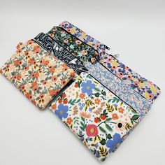 four different colored flowered cloths sitting next to each other on a white surface