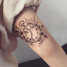 a woman's arm with a clock and flowers tattoo design on the left forearm