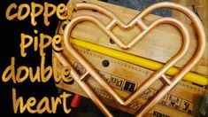 a heart shaped metal object sitting on top of a wooden table next to a ruler