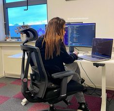 a woman sitting in front of a computer on top of a desk