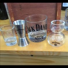 several glasses are lined up on a wooden counter top, including one with the name jack daniels