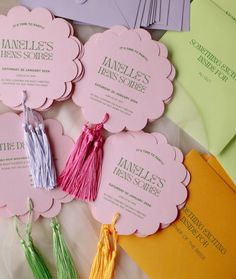 some tassels are laying on top of different colored envelopes and cards that have tassels attached to them