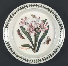 a plate with flowers and butterflies painted on the side, sitting on a black surface