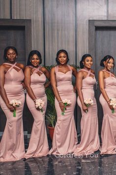 a group of women standing next to each other in long pink dresses and holding bouquets