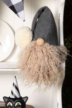 a black and white cat sitting on top of a shelf next to a gnome hat