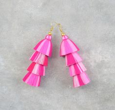 the pink tasselled earrings are hanging from gold hooks