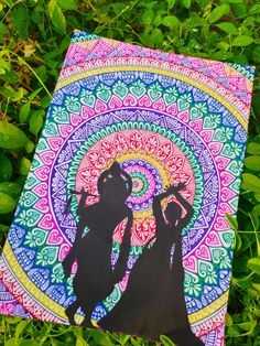 two people are standing in the grass with a colorful painting on it's side