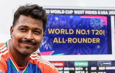 a man in an orange and blue shirt standing next to a sign that says world no 1 t20 all - rounder