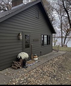 a gray house with a tree trunk and flowers on the front porch next to it