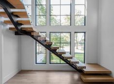 an empty room with wooden stairs and large windows