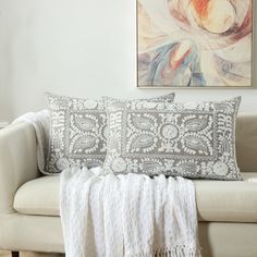 a white couch sitting next to a painting on the wall